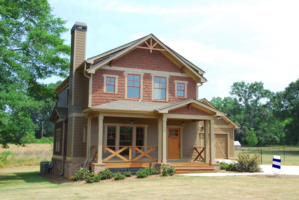 Charming single-family home with a porch, lawn, and trees, ideal for real estate use.